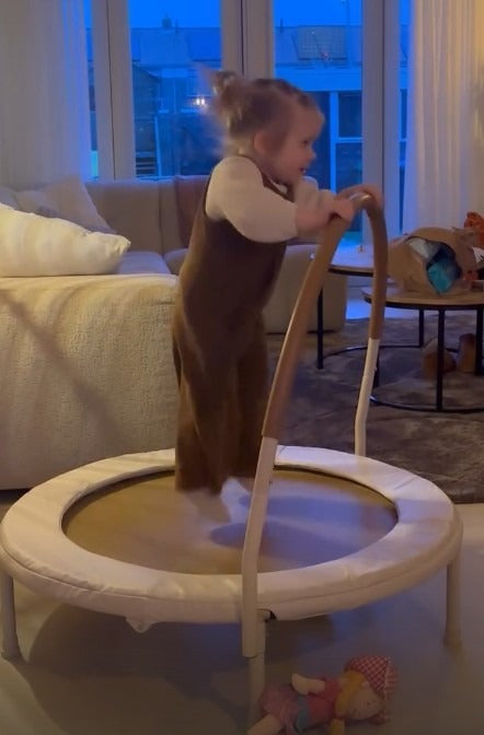 Peuter springt op de trampoline in de woonkamer