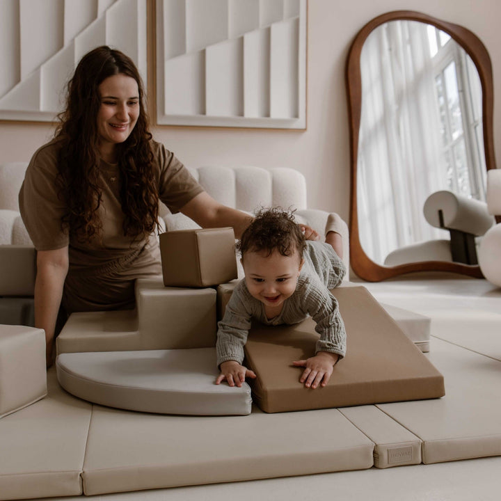 Baby kruipt van de zachte glijbaan terwijl de moeder meespeelt
