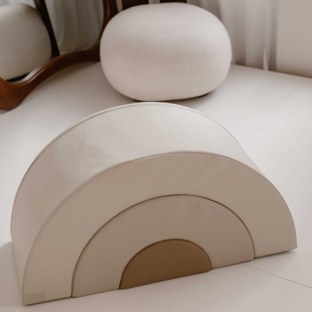 Drie zachte balansbogen in crème, beige en zandkleur opgesteld in een kinderkamer