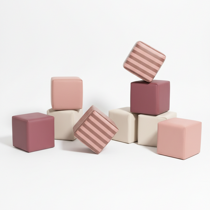 Kind speelt met gestreepte HENVAE stapelblokken in roze, beige, merlot en Merlot Rose.