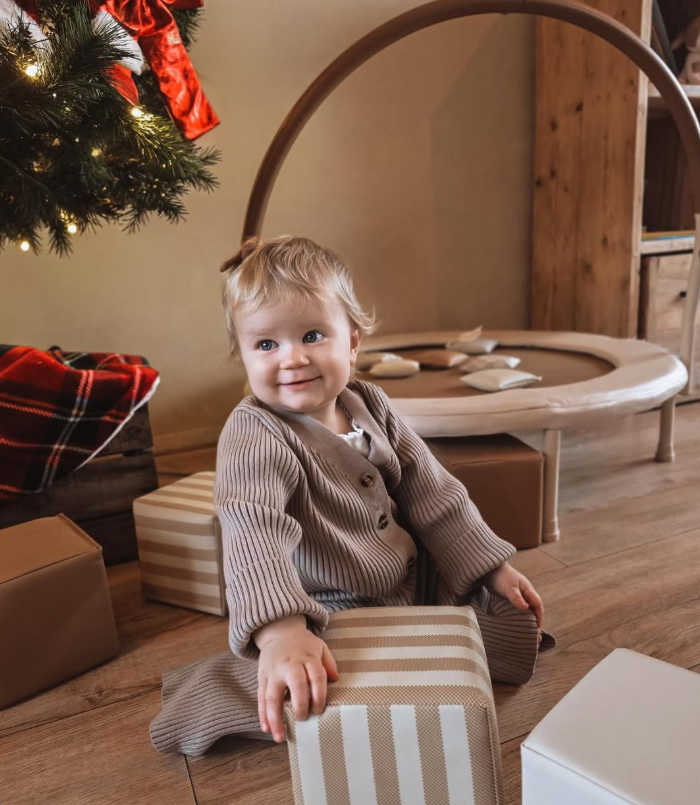 Baby speelt met gestreepte zachte blokken bij de kerstboom