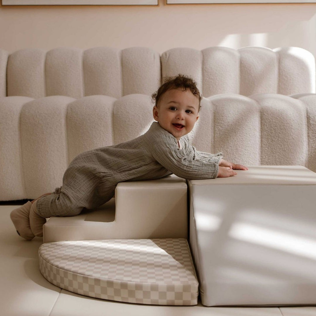 Lachende baby klimt over de 5-delige HENVAE baby speelset in Retro kleuren.