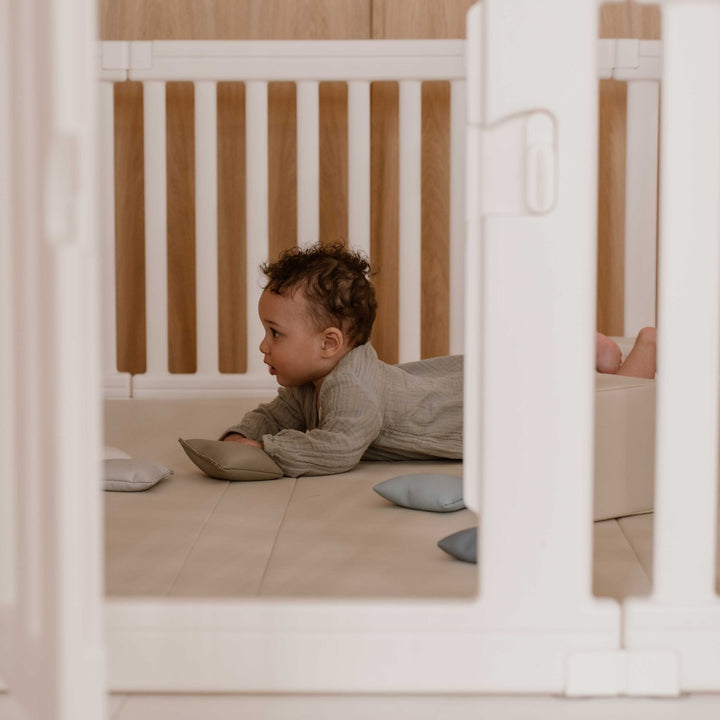 Baby speelt op de zachte beige speelmat in de minimalistische grondbox