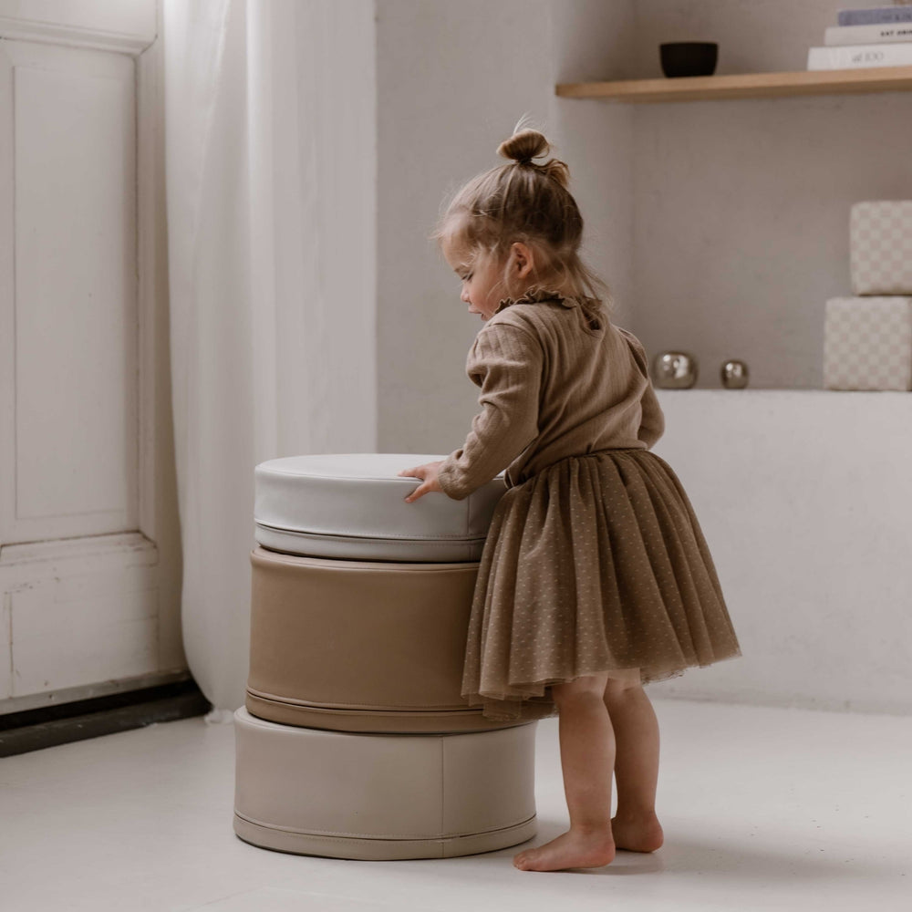 Meisje bouwt een toren met zachte stapelstenen in beige en taupe